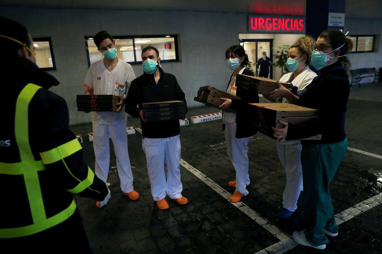 Personal sanitario del Hospital Madrid Sanchinarro recoge unas pizzas a la entrada de Urgencias.