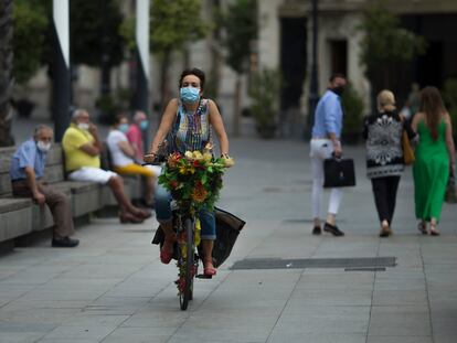 Una mujer con mascarilla pasea en bicicleta por el centro de Sevilla a principios de septiembre.