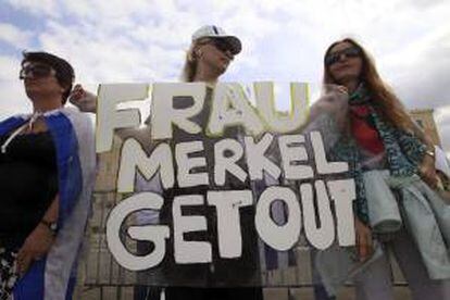 Una manifestante sujeta una pancarta en la que se puede leer "Frau Merkel Lárgate" durante una protesta frente la sede parlamentaria griega, en Atenas, Grecia, hoy.