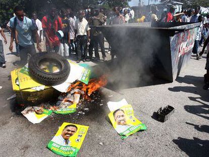 Haitianos queman pasquines del candidato presidencial Jude Celestin, como protesta contra los cascos azules.
