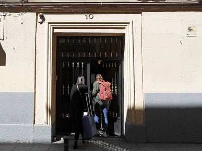 Dos personas con maletas entran en un edificio del centro de Madrid, el pasado febrero.