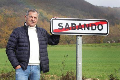 Ángel Marcos Pérez de Arrilucea, alcalde de Sabando, junto al cartel de entrada al municipio; al fondo, los montes comunales. 