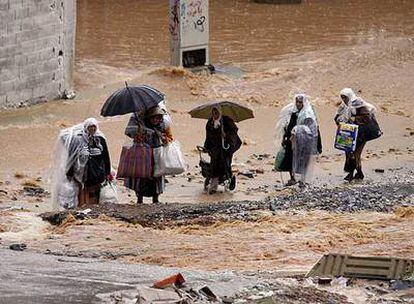 Un grupo de mujeres se desplaza con enseres bajo la lluvia y junto a torrentes de agua en Ceuta.