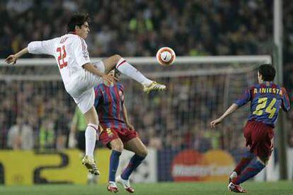 Iniesta se dispone a interceptar un pase forzado de Kaká por delante de Puyol.