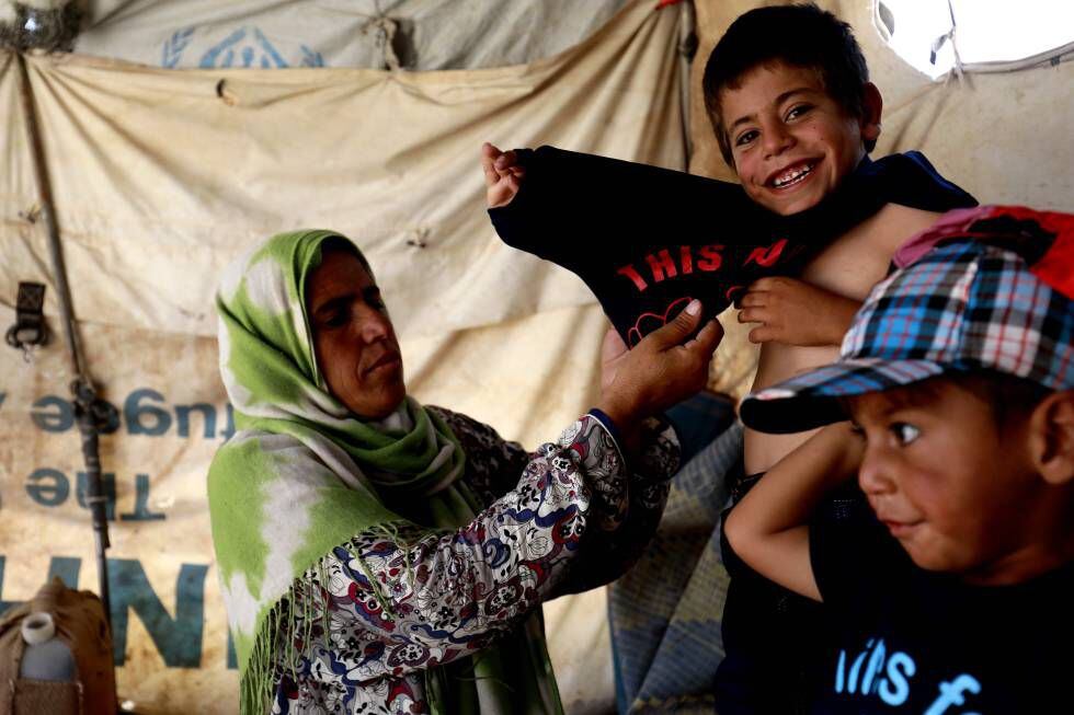 Una madre viste a sus hijos con ropa recibida de organizaciones internacionales en el campo de desplazados internos de Hasakeh (Siria).