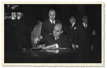 Julio Mu&ntilde;oz Ramonet es disposa a signar un document, sota l&rsquo;atenta mirada del seu germ&agrave; &Aacute;lvaro, als anys cinquanta.