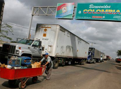 Un comerciante transita por la frontera venezolana con Colombia frente a una caravana de camiones.
