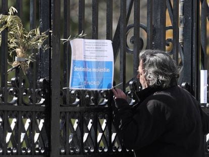 Un viandante mira un cartel que anuncia el cierre temporal del parque del Retiro en la puerta de Reina Mercedes.