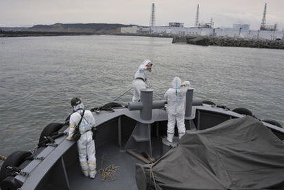 Miembros de la Marina japonesa, con trajes para protegerse de la radiación, en un barco que lleva agua pura al muelle de la central de Fukushima.