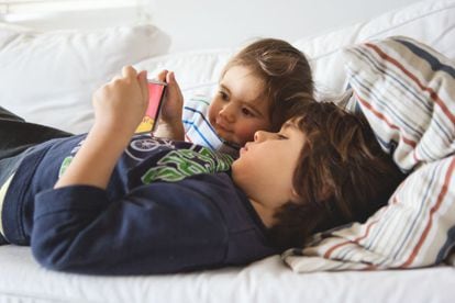 Uno niños miran dibujos animados en un dispositivo móvil en casa.