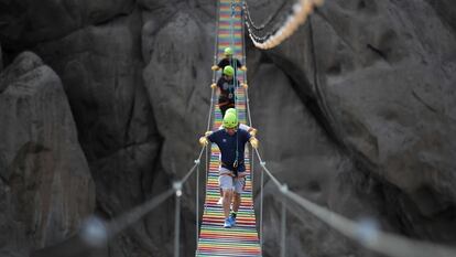 Varias personas cruzan un puente colgante de las Lomas del Mirador, en San Juan de Lurigancho (Perú).