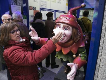 Una mujer frota su d&eacute;cimo en el Jorobado de la Suerte, una administraci&oacute;n en la calle Preciados de Madrid.