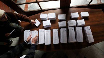 Dos personas escogen papeletas para votar en un centro electoral de Barcelona.