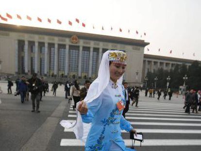 Una delegada de una minoría étnica cruza corriendo un paso de cebra tras asistir a una sesión plenaria de la Conferencia Consultiva Política del Pueblo Chino en Pekín.