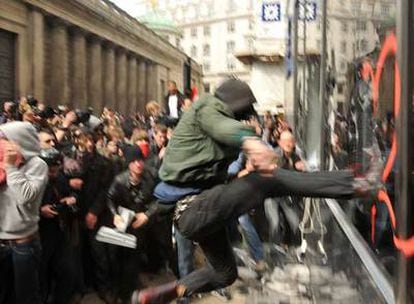 Un manifestante patea el escaparate de una oficina de Royal Bank of Scotland en Londres.