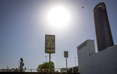 Una mujer pasa junto a un termómetro que marca 48º al sol frente a Torre Sevilla, el pasado 18 de junio.