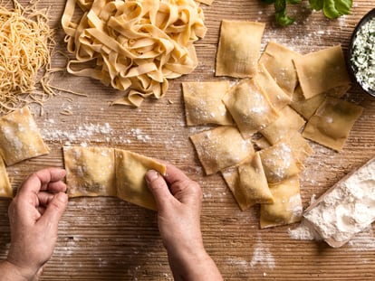 Una mujer prepara diferentes tipos de pasta como espaguetis, tallarines y raviolis en la cocina de su hogar.