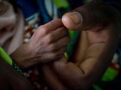 Hadida, de cinco meses y con malnutrición aguda severa agarra el dedo de su madre, Fátima, en el hospital de Diffa, en Níger.