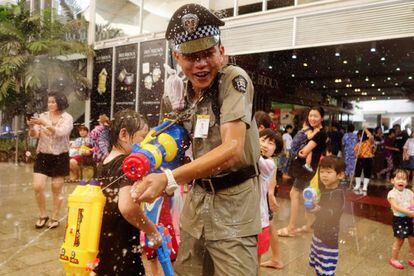 Las autoridades de la capital tailandesa han habilitado una docena de espacios de la ciudad que se han transformado en batallas campales de agua con pistolas de plástico y cualquier otro utensilio, como cazos y cubos. En la fotografía, un oficial de seguridad participa en una de las guerras de agua de Bangkok.