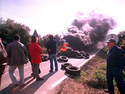 Un grupo de payeses ante una barricada de neumáticos incendiada.