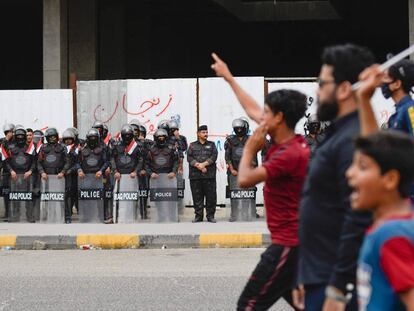 Manifestantes iraquíes marchan frente a fuerzas antidisturbios, en la ciudad iraquí de Najaf.