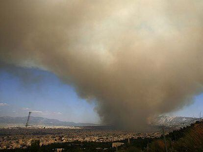 Una nube de humo provocada por el incendio sobre la montaña Pendelis se extiende ayer sobre Atenas.
