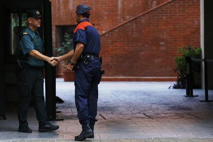 Un mosso d'esquadra saluda a un guardia civil en la entrada de la caserna de Travessera de Gracia, en Barcelona, donde permanecían varios de los 14 detenidos en Cataluña por delitos de malversación, prevaricación y desobediencia.