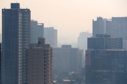 Santiago de Chile ha amanecido este viernes cubierto por una nube de humo; una mezcla de gases y partículas de árboles y materiales producto de un centenar de incendios forestales, concentrados en la zona central del país. En la imagen, edificios en la zona central de Santiago rodeados por el humo. 