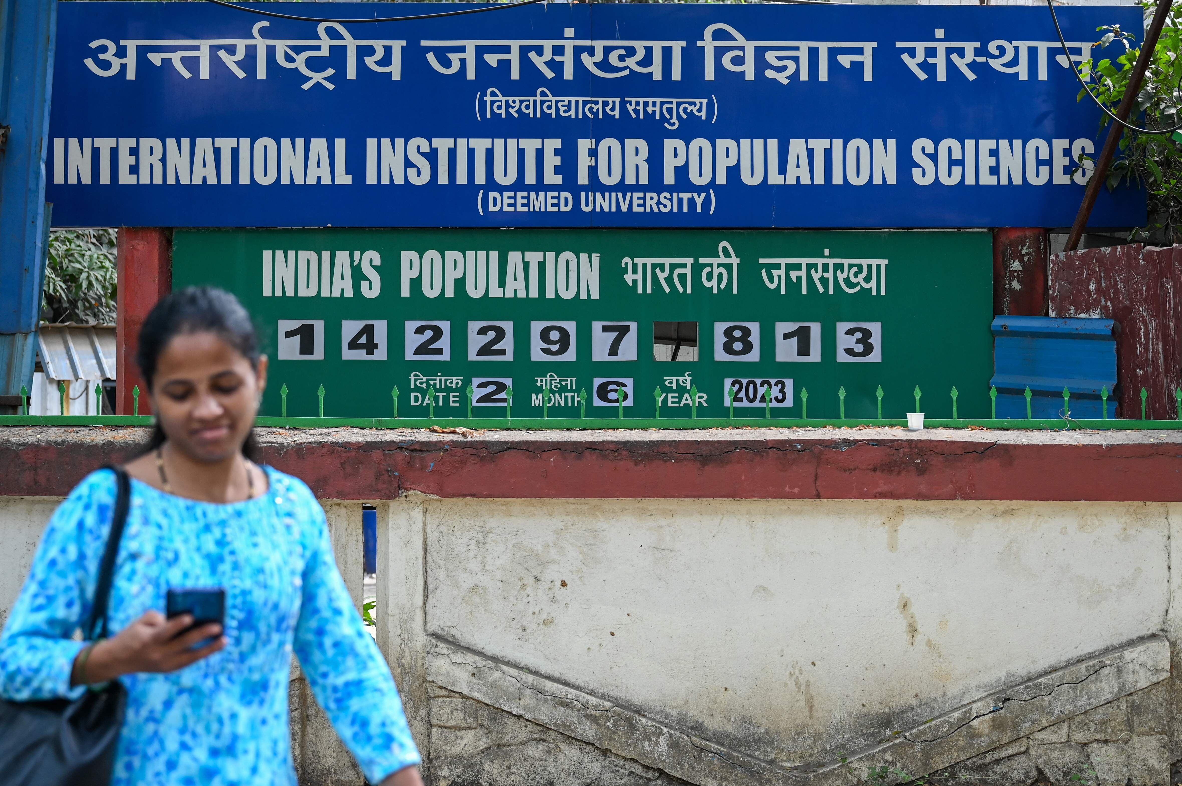 Una mujer pasa ante el contador de población instalado en el exterior del Instituto Internacional de Ciencias de la Población en Bombay, el 2 de junio de 2023. 