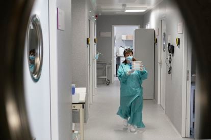 Centre national de microbiologie, Institut de santé Carlos III, à Majadahonda (Madrid).  Un technicien du centre porte des flacons de culture.  Ce milieu rose sert de nourriture aux cellules qui se développent, se multiplient et, si elles sont infectées, produisent des virus.