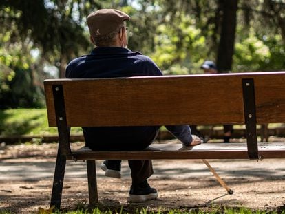 Un hombre mayor sentado en un banco de un parque de Madrid.