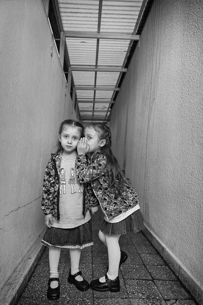A la derecha, Lubna, de seis años y medio, le habla al oído a su hermana Elunei, de cuatro, en el pasillo de la casa de su abuela en la ciudad de La Plata (Argentina). Cuando nació, Lubna pesaba 960 gramos.