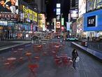 A woman walks through a lightly trafficked Times Square in New York, Monday, March 16, 2020. Bars and restaurants will become takeout-only and businesses from movie theaters and casinos to gyms and beyond will be shuttered Monday night throughout New York, New Jersey and Connecticut because of the coronavirus, the states' governors said. (AP Photo/Seth Wenig)