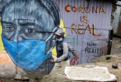 Un hombre pasa delante de un grafiti que advierte sobre el coronavirus en el asentamiento de Mathare, en Nairobi, capital de Kenia.