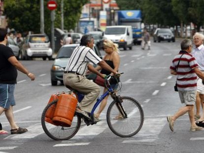 Un hombre carga en su bici con dos bombonas.