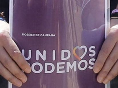 El l&iacute;der de Podemos, Pablo Iglesias, sostiene el dossier de campa&ntilde;a con el logo de Unidos Podemos.