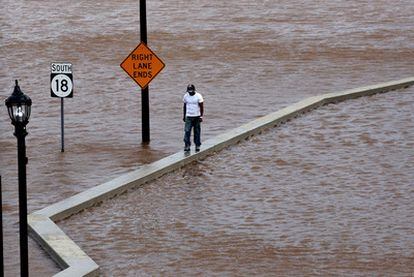 Un hombre camina por encima de una pared para poder desplazarse en New Brunswick, Nueva Jersey, durante las inundaciones provocadas por el paso del huracán Irene