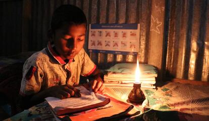 Un niño hace sus tareas escolares en su casa, bajo la luz de una vela, en una aldea de Bangladés.