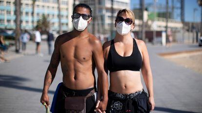 Una pareja con mascarillas practica ejercicio en el litoral de Barcelona.