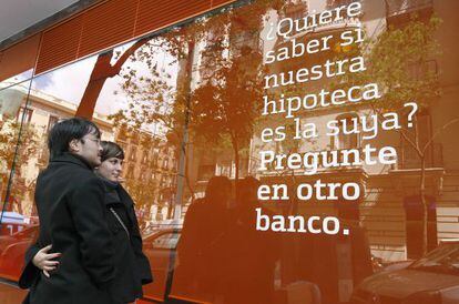 Una pareja lee un anuncio de una hipoteca en una ofician bancaria.