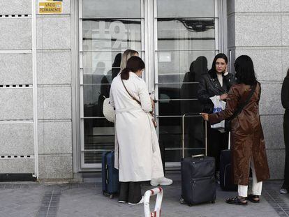 Varias personas esperan en el portal de un edificio con pisos de alquiler para uso turístico, en Madrid.