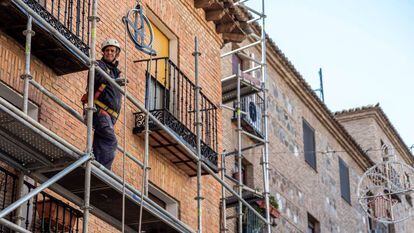 Un obrero de la construcción trabaja sobre un andamio en una calle en Toledo.