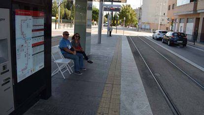 Dos personas sentadas en las sillas que pusieron los propios vecinos en la estación del tranvía de avenida de la Academia en Zaragoza.