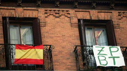 La bandera nacional junto a un mensaje contra el presidente del Gobierno en unos balcones de Madrid.