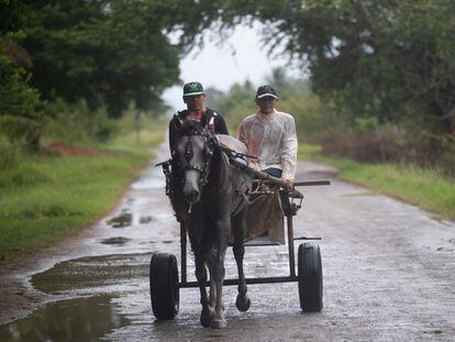 Dos personas transitan sobre una carreta tirada por un caballo, en Coloma, poblado de la provincia Pinar del Río por la que está previsto entrará el huracán 'Ian'.