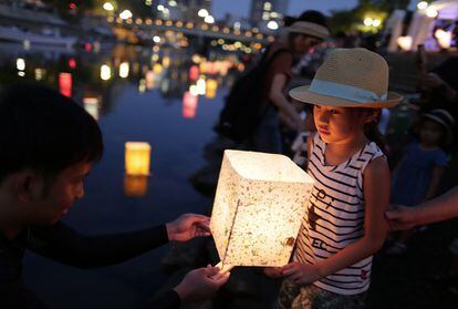 Una niña sujeta una linterna de papel para depositarla en el río por la conmemoración del bombardeo atómico en el Parque Memorial de la Paz en Hiroshima (Japón). 