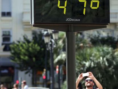 Un hombre toma una fotograf&iacute;a a un term&oacute;metro en Valencia, en agosto.