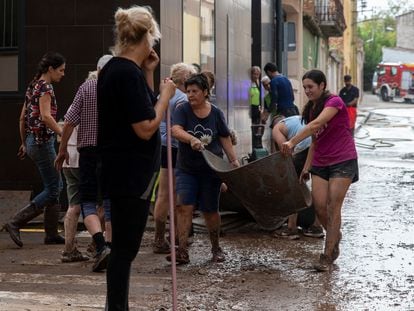 Varios vecinos trabajan en achicar agua y barro, este domingo en Santa Barbara, Tarragona.