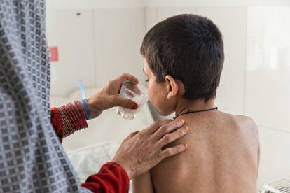 Saed Bibi le está dando un vaso de leche a su hijo Saddiqulah, de 10 años, en la pediatría del hospital de Boost, apoyado por MSF. El niño tiene
sarampión, lo que le ha llevado a desarrollar neumonía y sepsis severa.