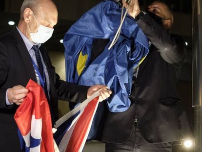 Dos empleados de la Comisión Europea sustituyen banderas de la Unión y de Reino Unido en el exterior del edificio. 